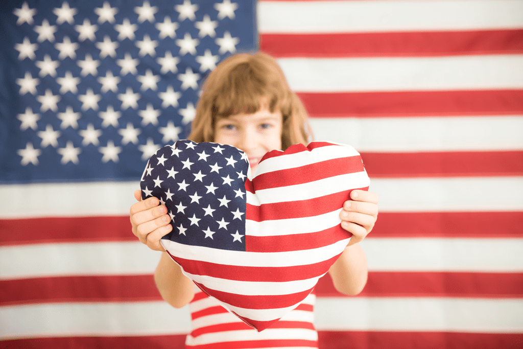 girl holding American flag heart pillow with flag background