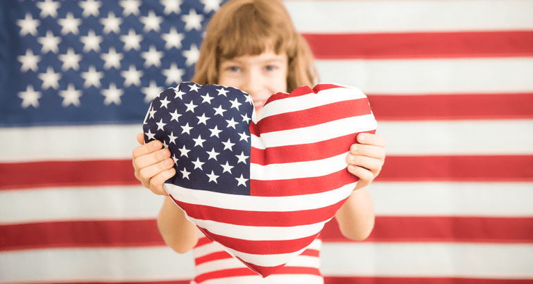 girl holding American flag heart pillow with flag background
