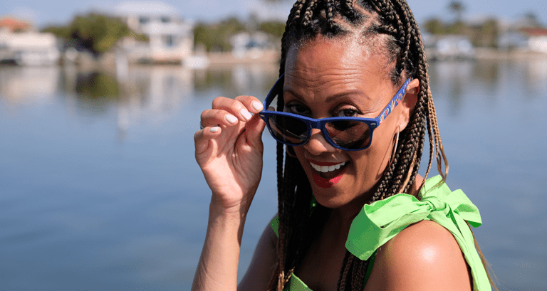 PPW Expo host Anji Corley peeks over a pair of branded sunglasses with a smile