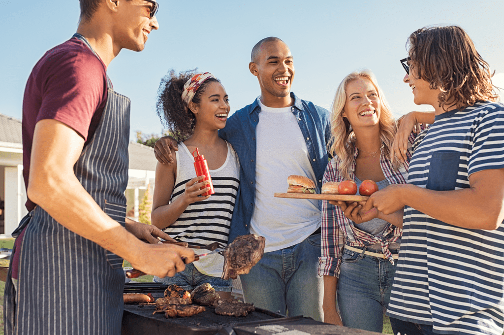 friends at backyard BBQ enjoy grilled steak and veggies