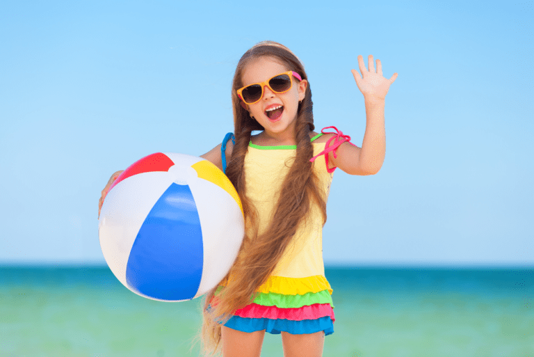 Little girl on beach with sunglasses and beach ball