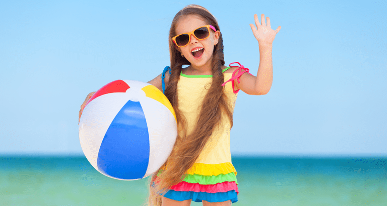 Little girl on beach with sunglasses and beach ball