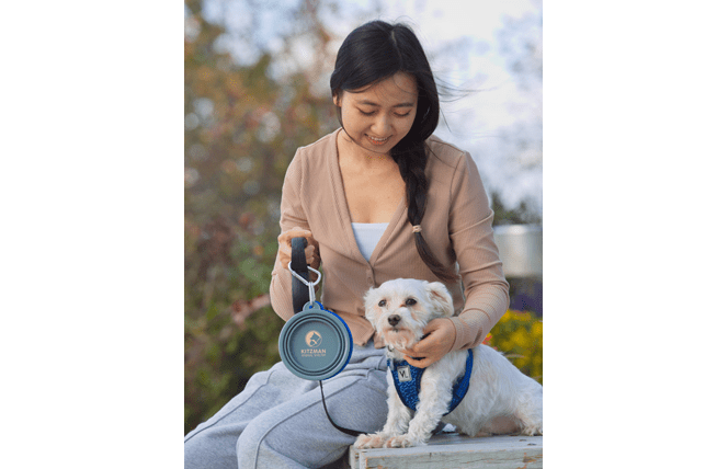 Asian woman with pet dog, holding a collapsible pet water bowl