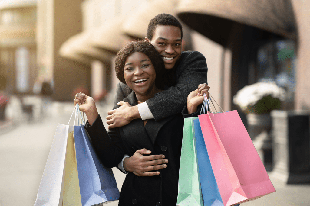 happy couple - man embracing woman holding colorful shopping bags
