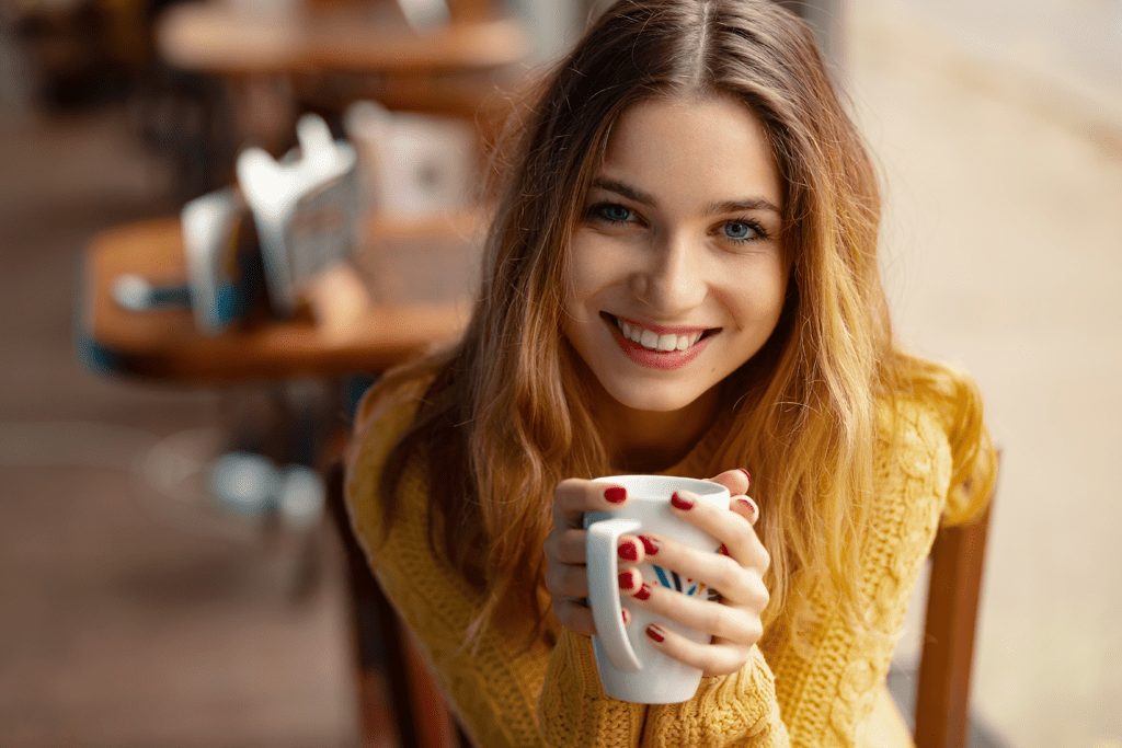 woman smiling over her cup of coffee