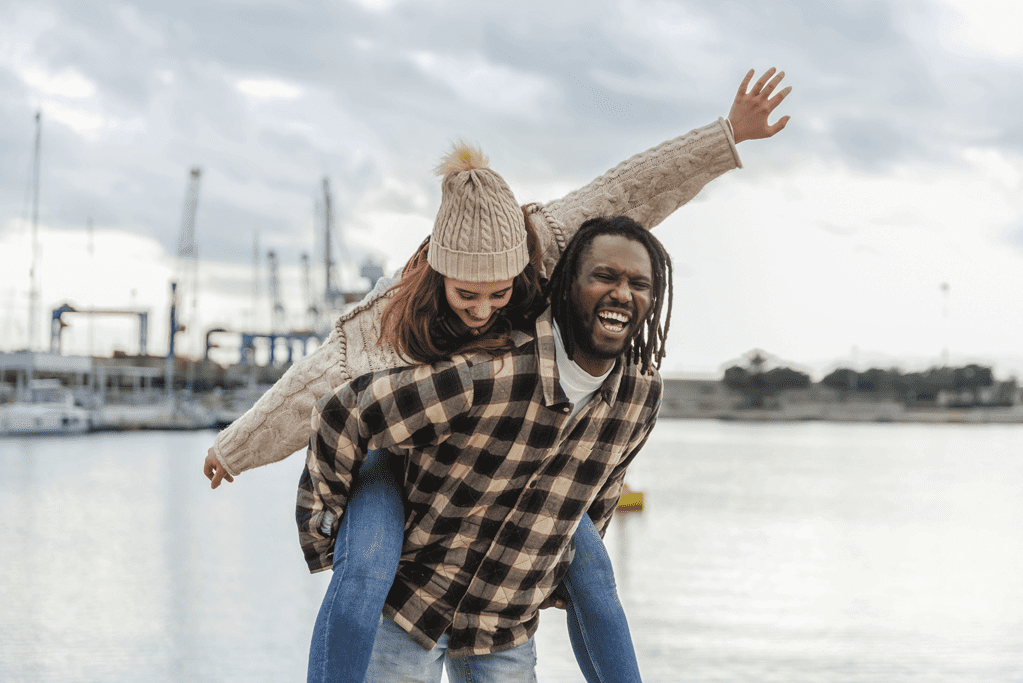 couple laughing and playing in cold weather outside near the docks