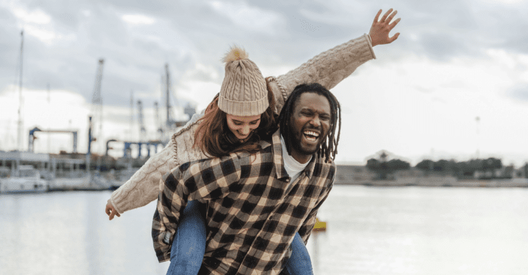 couple laughing and playing in cold weather outside near the docks