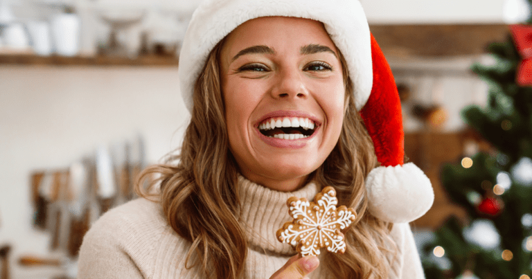 smiling woman in Santa hat holding snowflake cookie