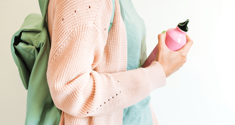 woman with backpack carrying reusable water bottle