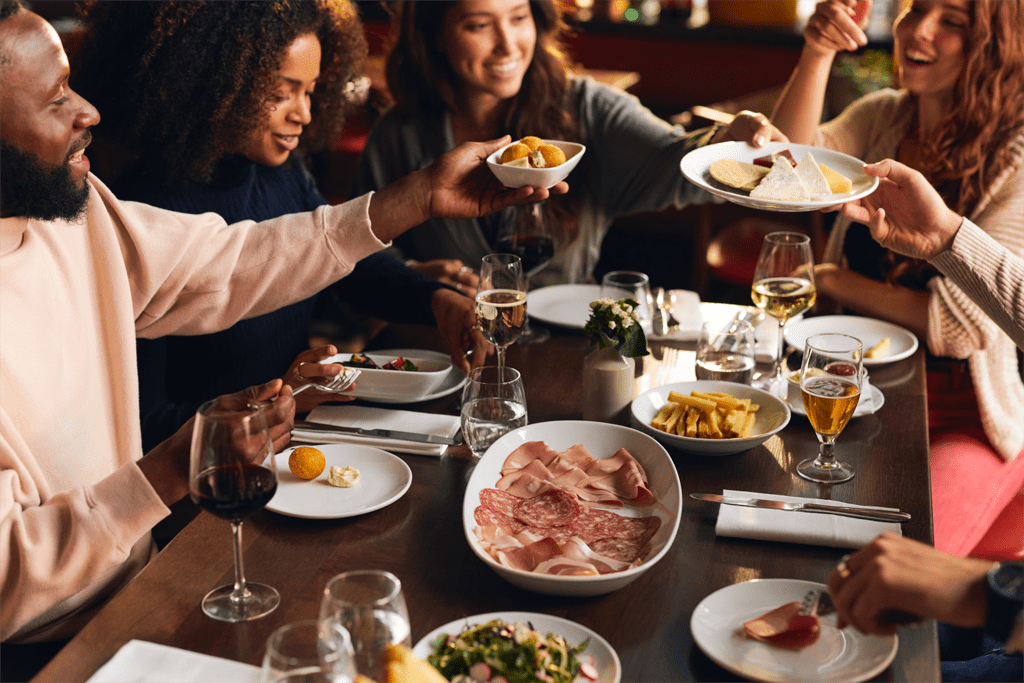 friends around a restaurant table happy sharing plates