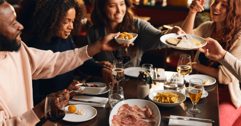 friends around a restaurant table happy sharing plates
